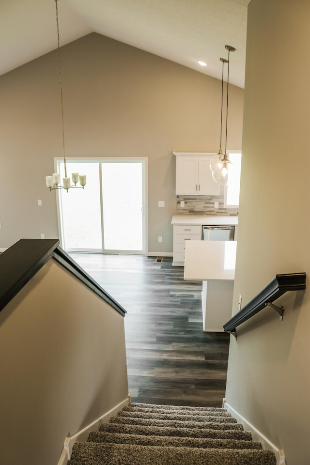 stairway featuring a notable chandelier, wood finished floors, baseboards, and high vaulted ceiling