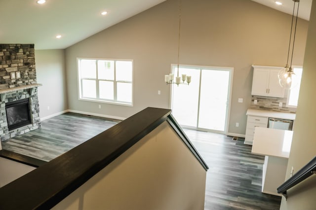 interior space featuring high vaulted ceiling, a fireplace, white cabinets, pendant lighting, and tasteful backsplash