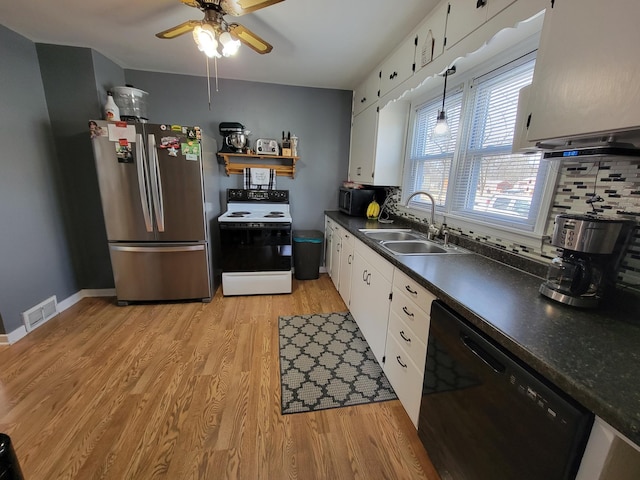 kitchen featuring a sink, decorative backsplash, black appliances, light wood-style floors, and dark countertops