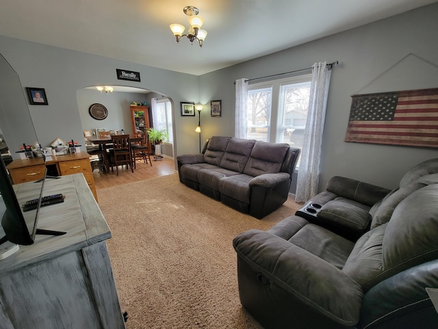 living room featuring baseboards, arched walkways, an inviting chandelier, and light wood finished floors