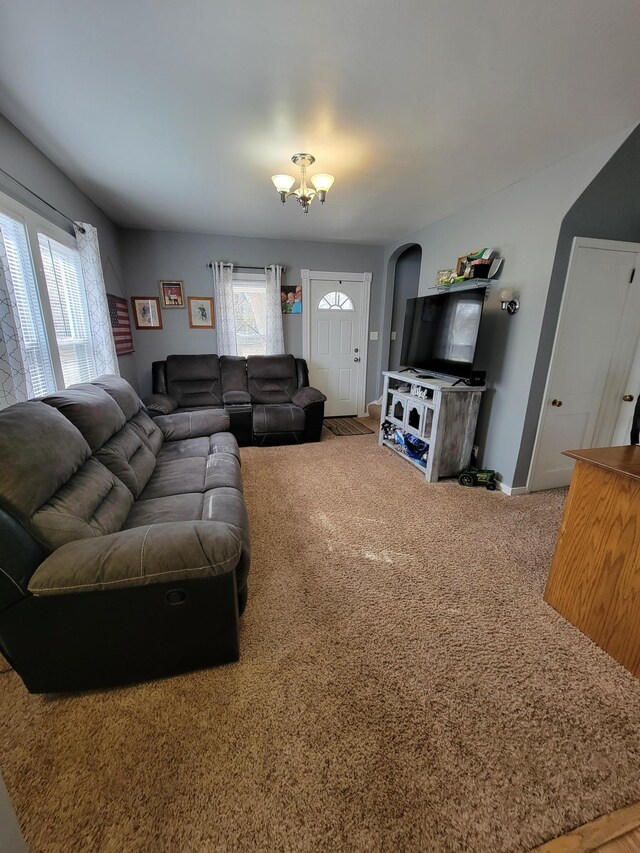 carpeted living area with an inviting chandelier