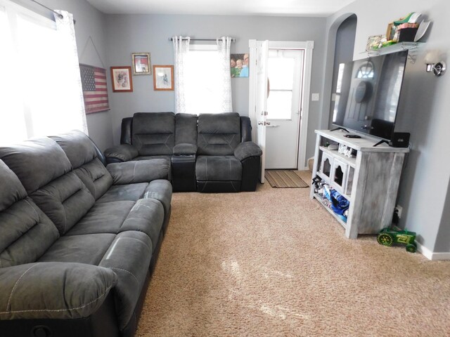 living area featuring arched walkways and light colored carpet