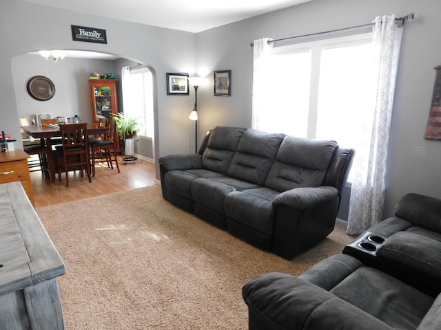 living room featuring baseboards, arched walkways, and wood finished floors