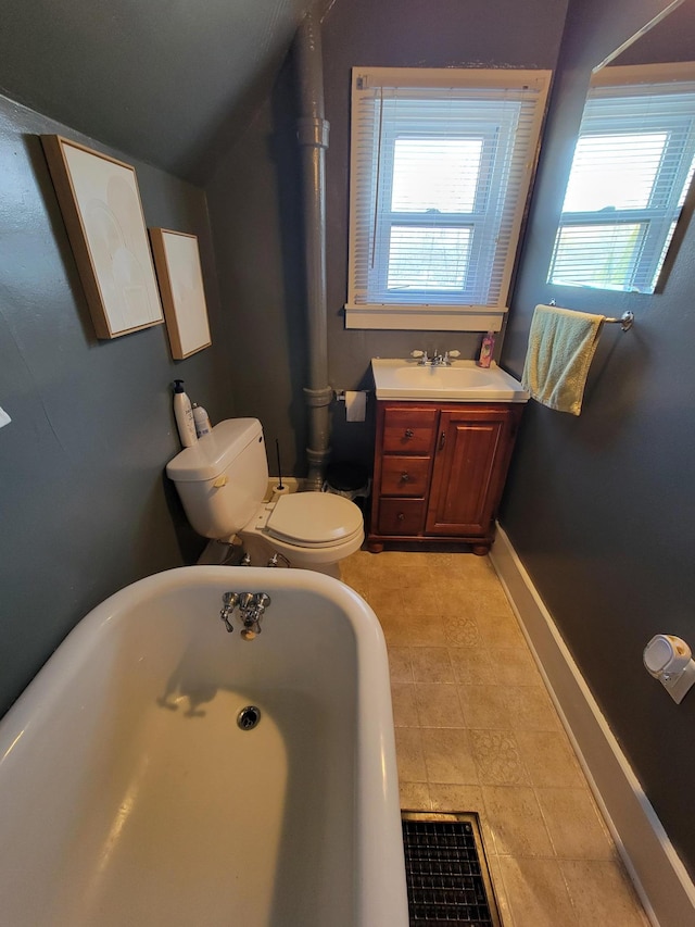 bathroom featuring vanity, baseboards, a soaking tub, lofted ceiling, and toilet