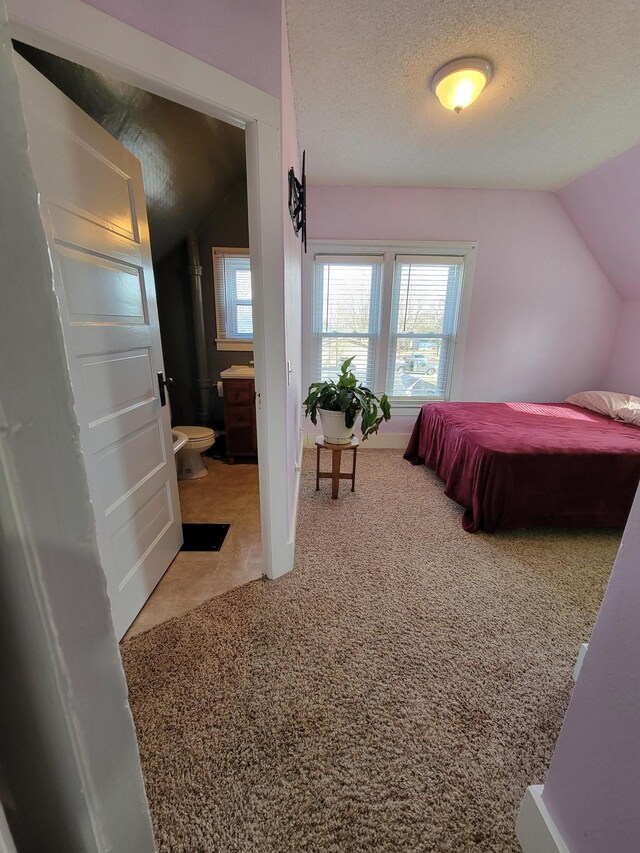 carpeted bedroom featuring a textured ceiling and lofted ceiling