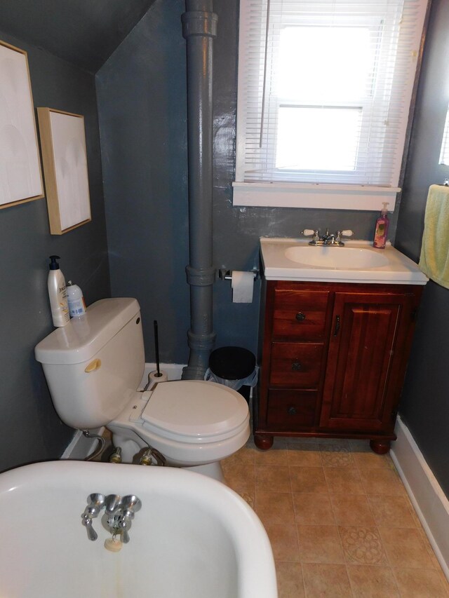 bathroom featuring tile patterned floors, toilet, lofted ceiling, a freestanding bath, and vanity