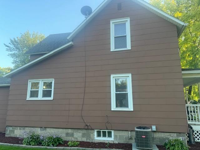 view of home's exterior featuring central AC and a shingled roof