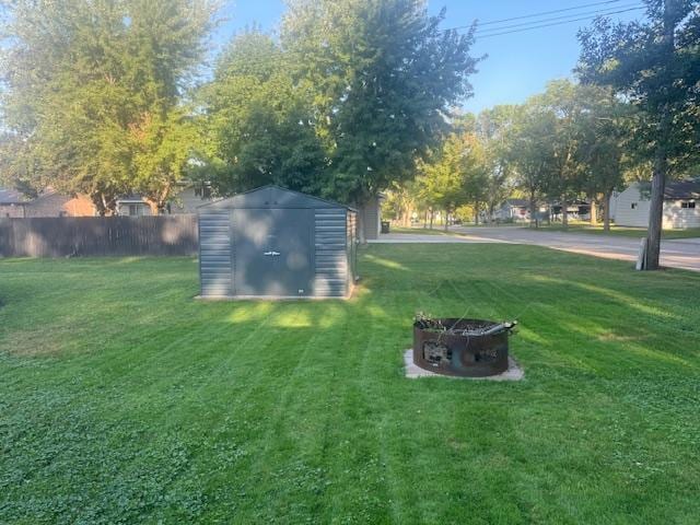 view of yard featuring a storage unit, an outdoor fire pit, an outdoor structure, and fence