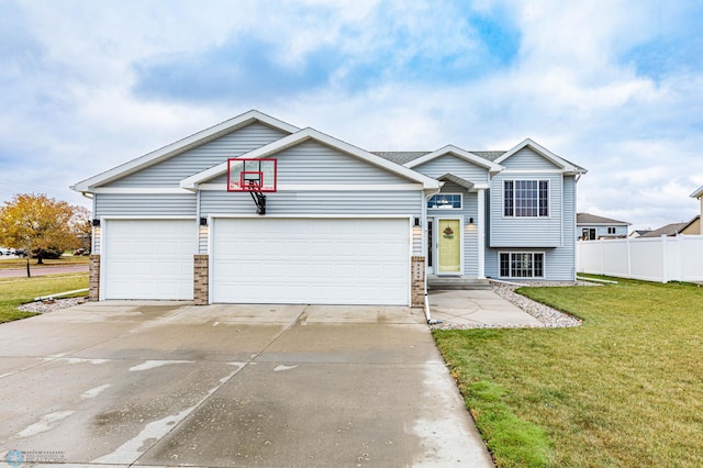 view of front of house with a garage, driveway, a front lawn, and fence