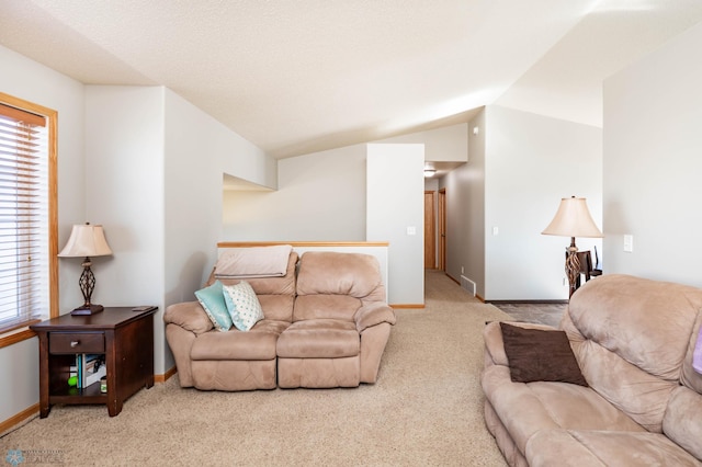 carpeted living area featuring plenty of natural light, visible vents, baseboards, and vaulted ceiling