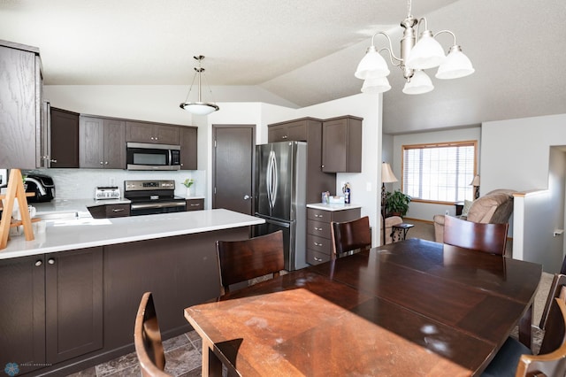 kitchen featuring dark brown cabinetry, light countertops, lofted ceiling, appliances with stainless steel finishes, and a peninsula