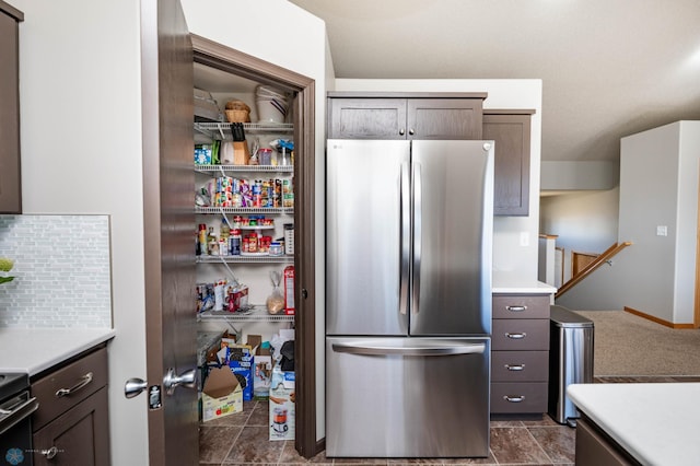 kitchen featuring backsplash, light countertops, and freestanding refrigerator