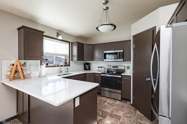 kitchen featuring a sink, appliances with stainless steel finishes, a peninsula, light countertops, and decorative backsplash