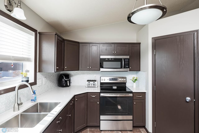 kitchen with dark brown cabinetry, appliances with stainless steel finishes, lofted ceiling, and a sink