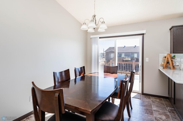 dining room with baseboards, lofted ceiling, and a chandelier