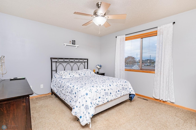 bedroom with visible vents, baseboards, a textured ceiling, and a ceiling fan