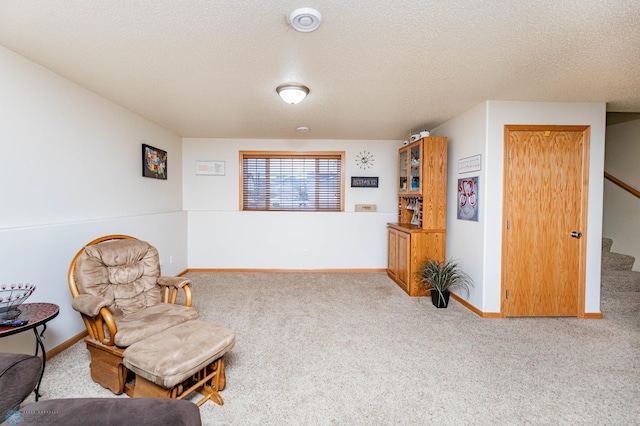 living area featuring stairway, baseboards, carpet floors, and a textured ceiling