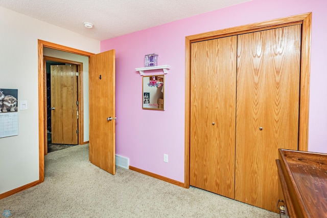 bedroom featuring baseboards, visible vents, a closet, a textured ceiling, and carpet flooring