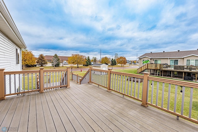 wooden terrace featuring a yard, a residential view, an outbuilding, and a storage shed