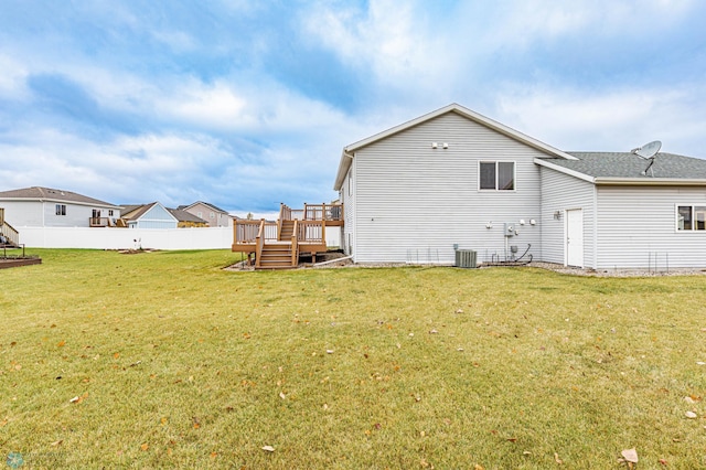 back of property featuring a lawn, central AC, a deck, and fence