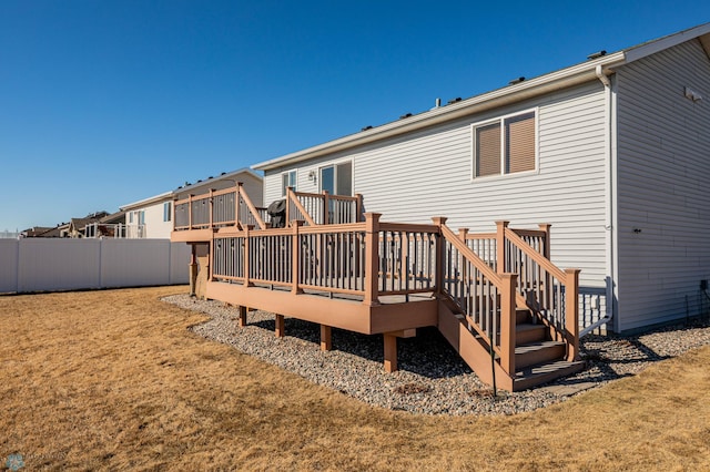 back of house with a wooden deck, a lawn, and fence