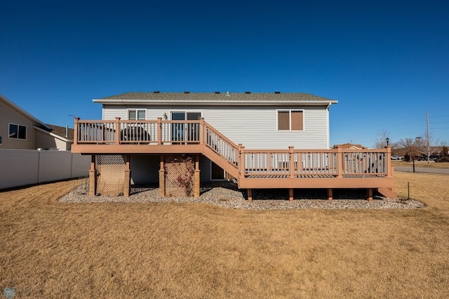 back of property with a wooden deck, a yard, and fence