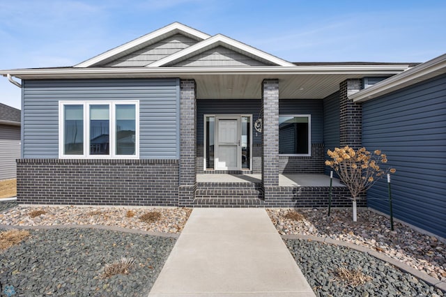 property entrance featuring brick siding and a porch