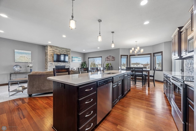 kitchen featuring light countertops, an island with sink, appliances with stainless steel finishes, an inviting chandelier, and a sink