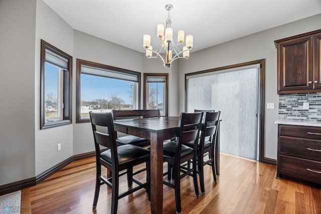 dining space featuring light wood-style flooring, baseboards, and an inviting chandelier