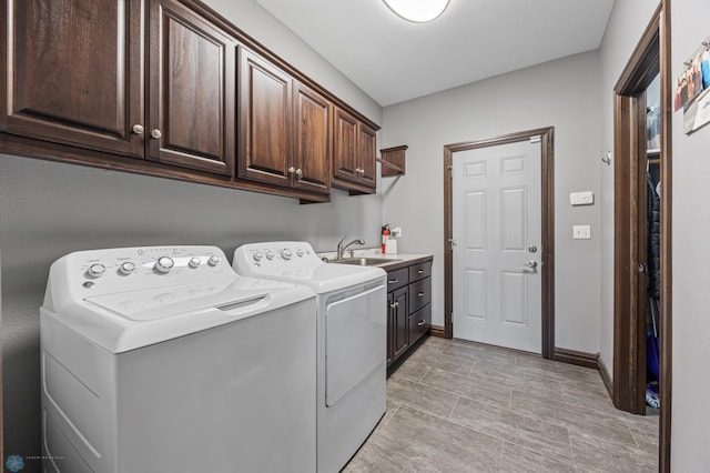 washroom featuring washer and dryer, baseboards, cabinet space, and a sink