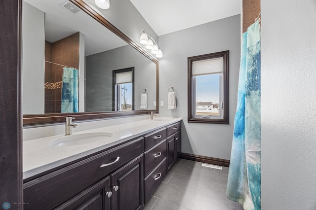 bathroom with tile patterned floors, visible vents, a sink, double vanity, and baseboards