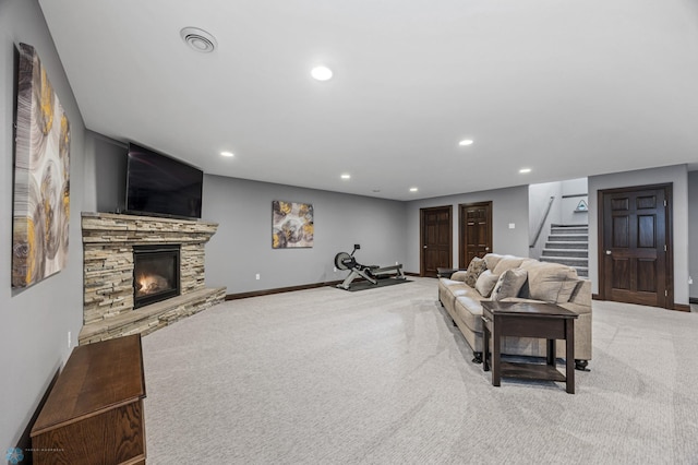 carpeted living area featuring visible vents, baseboards, a fireplace, recessed lighting, and stairs