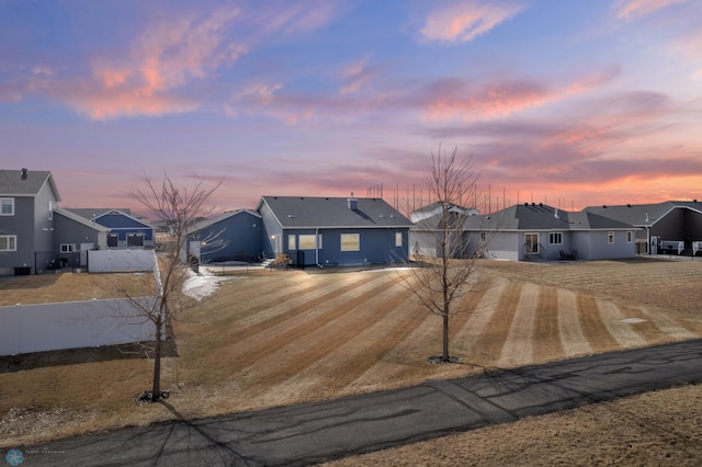 ranch-style house with a residential view, driveway, and fence