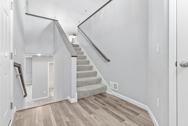 stairs with wood finished floors, visible vents, and baseboards