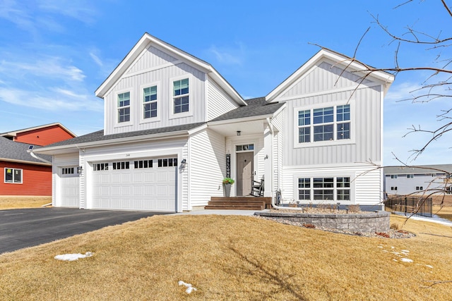 view of front facade with a front yard, a shingled roof, an attached garage, board and batten siding, and driveway