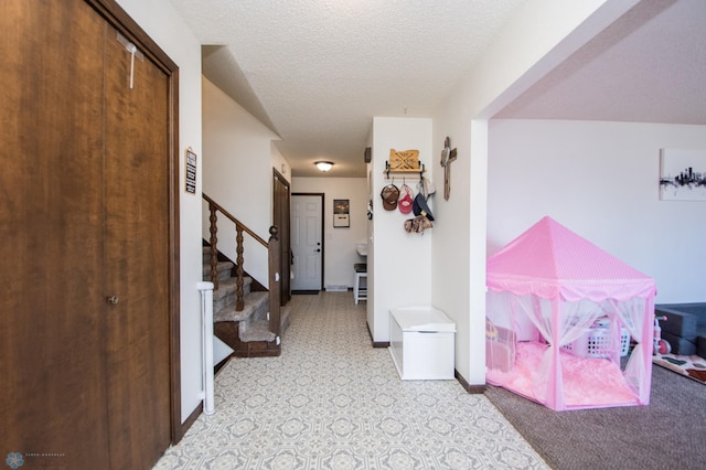 hall featuring baseboards, a textured ceiling, and stairs