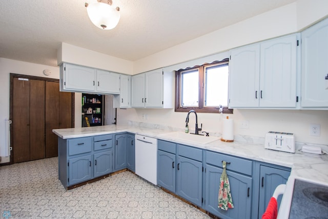 kitchen featuring light floors, dishwasher, a peninsula, blue cabinets, and a sink