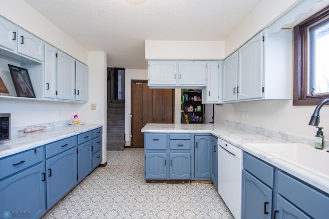 kitchen featuring blue cabinetry, white dishwasher, a sink, light countertops, and a textured ceiling