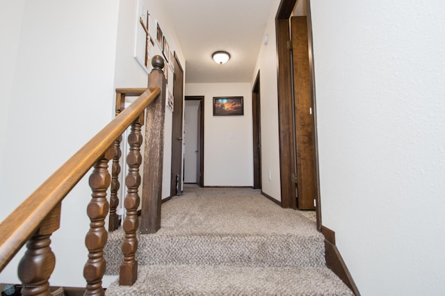 hallway with light carpet, stairway, and baseboards