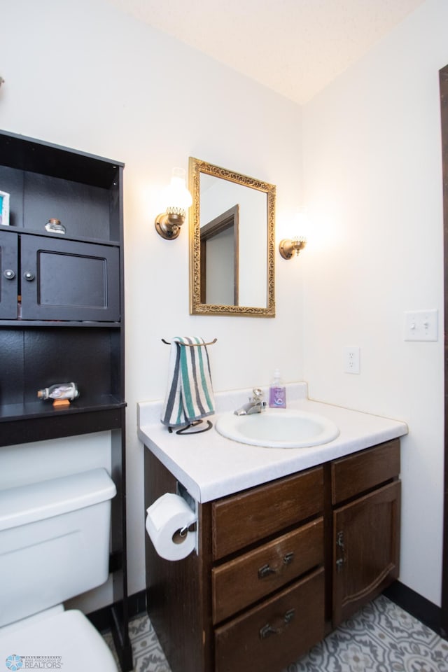 bathroom featuring toilet, vanity, and baseboards