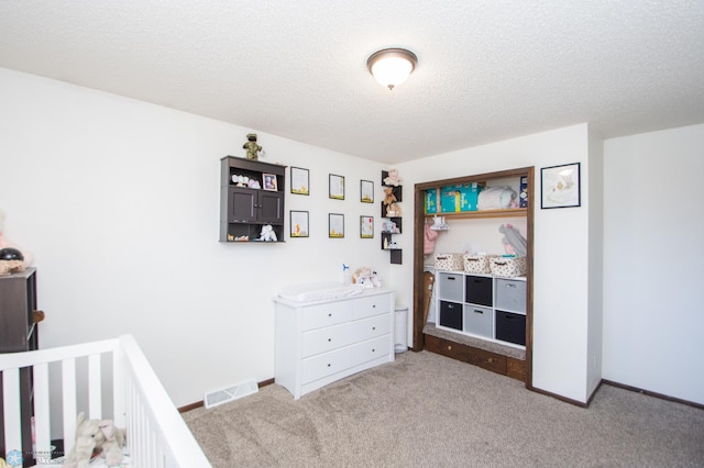 bedroom with visible vents, light carpet, a textured ceiling, and baseboards