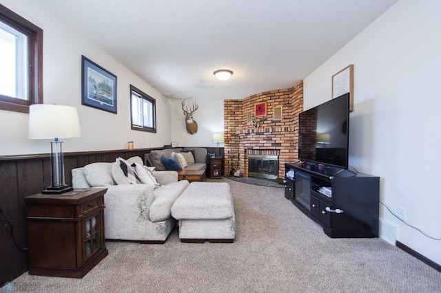 carpeted living room featuring visible vents, a fireplace, a wainscoted wall, and a textured ceiling