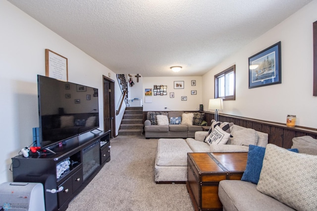 living room with wainscoting, a textured ceiling, stairs, and carpet