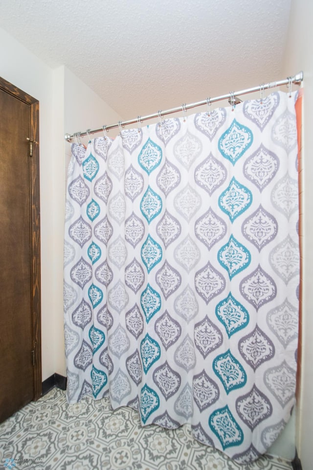 full bathroom featuring a shower with curtain and a textured ceiling