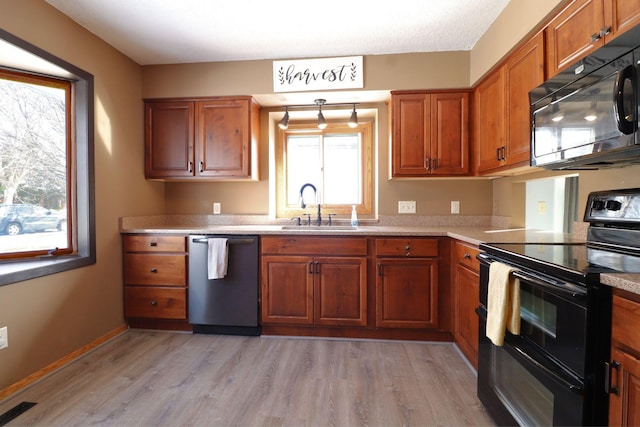 kitchen with a sink, visible vents, brown cabinets, and black appliances