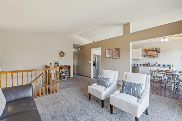 living area featuring carpet, ceiling fan, and vaulted ceiling