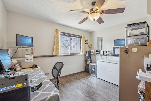 office featuring wood finished floors, a ceiling fan, baseboards, electric panel, and a textured ceiling