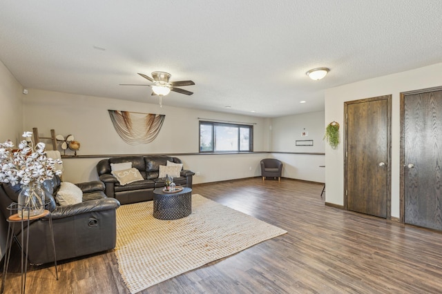 living area featuring a textured ceiling, wood finished floors, baseboards, and ceiling fan