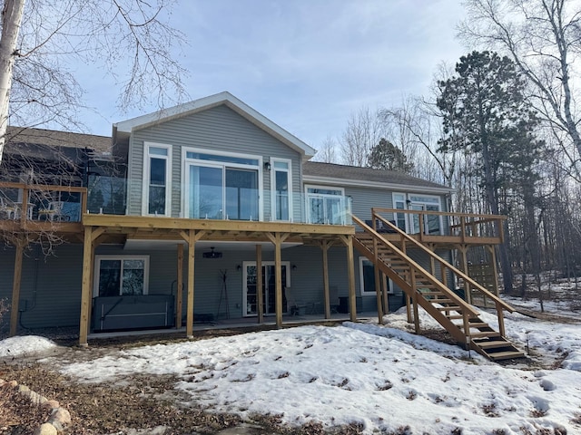 snow covered rear of property with stairway and a wooden deck