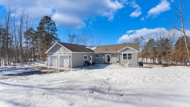 snow covered rear of property with an attached garage